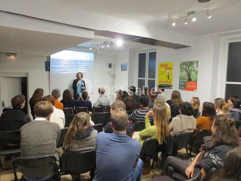 Un groupe de personnes assises dans une salle regarde une présentation projetée sur un écran.