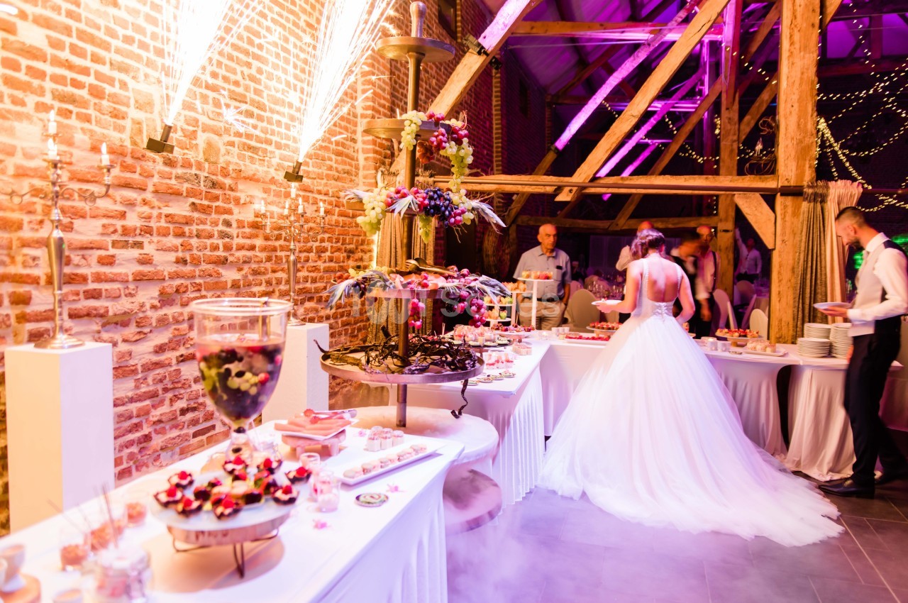 Buffet de desserts décoré avec une fontaine de chocolat dans une salle de réception éclairée par des lumières colorées.