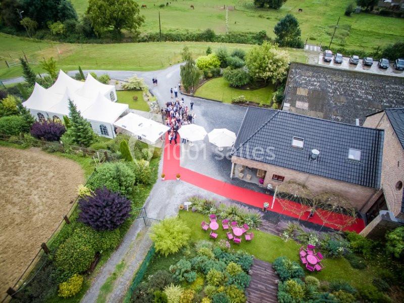 Vue aérienne d'un événement en extérieur avec tapis rouge, tentes blanches et espaces verts environnants.