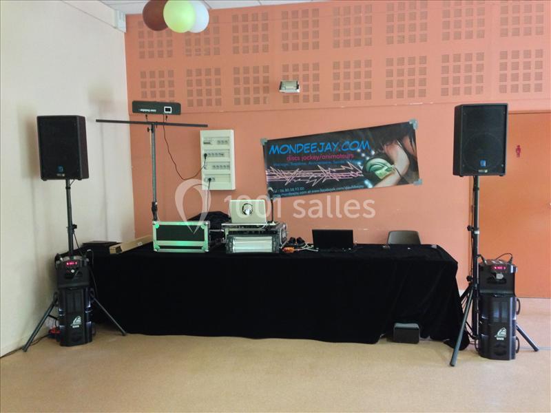 Installation de matériel de sonorisation avec table de mixage, enceintes et bannière publicitaire dans une salle.