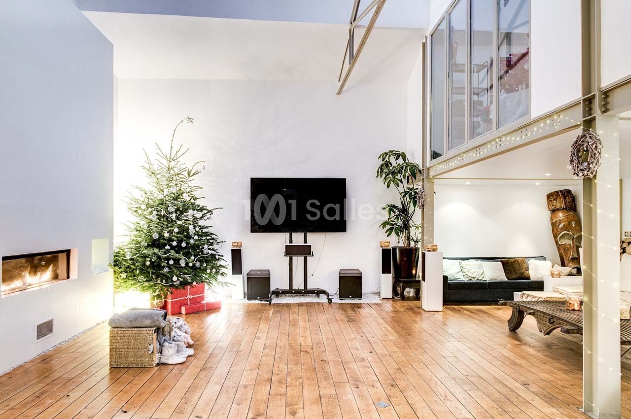Salon spacieux avec parquet, sapin de Noël décoré, cheminée moderne, télévision murale et mezzanine vitrée.