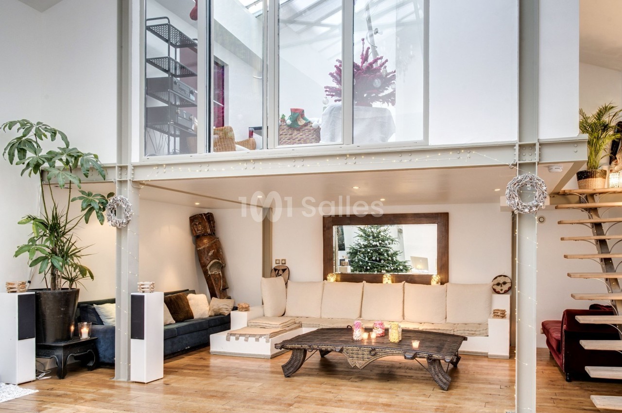 Salon lumineux avec mezzanine, canapé beige, table basse en bois, plantes et décoration chaleureuse dans un style moderne.