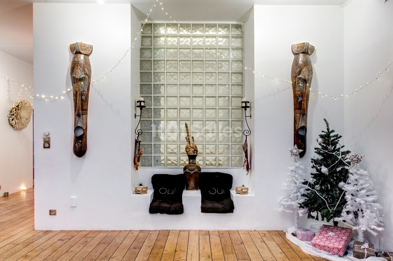 Deux sculptures murales en bois encadrent une niche décorée, avec un sapin blanc et des guirlandes lumineuses.