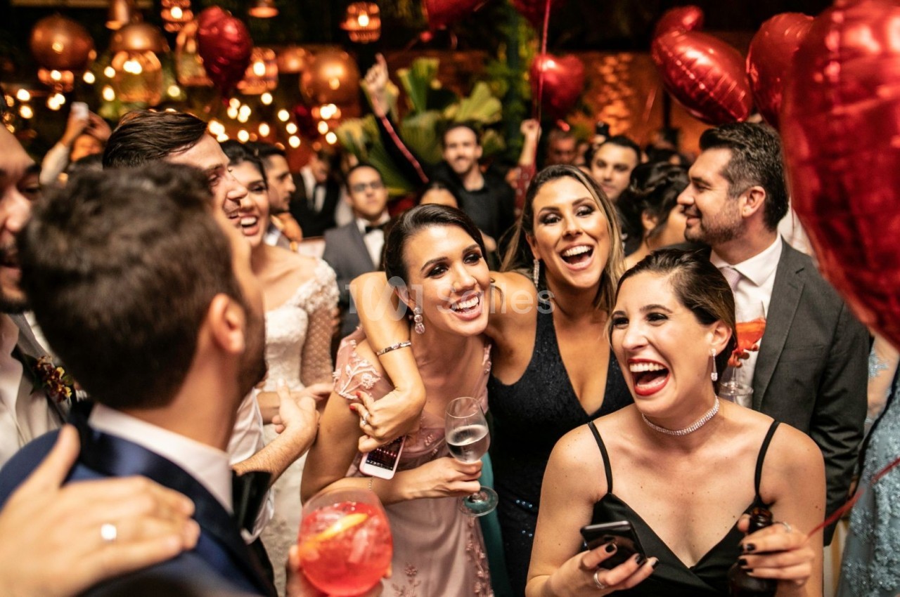 Groupe de personnes souriantes dans une ambiance festive avec des ballons rouges et des lumières tamisées.