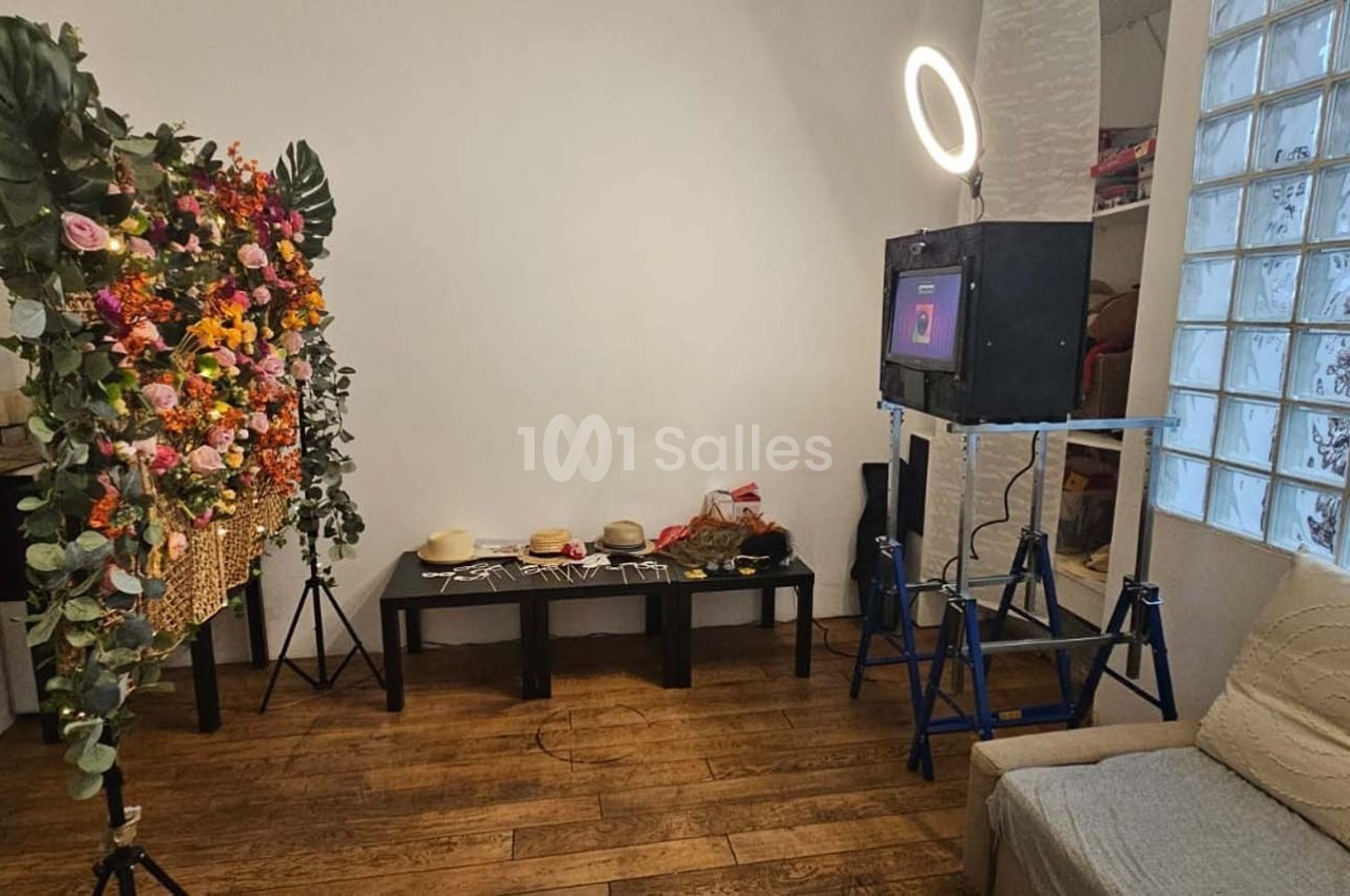 Installation de photobooth avec un écran, un éclairage circulaire et un décor floral dans une pièce lumineuse.