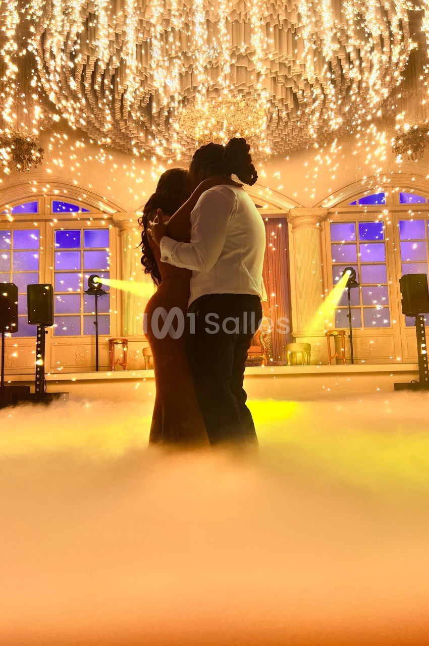 Un couple danse sous un plafond illuminé d'étincelles dans une salle élégante avec éclairage tamisé.