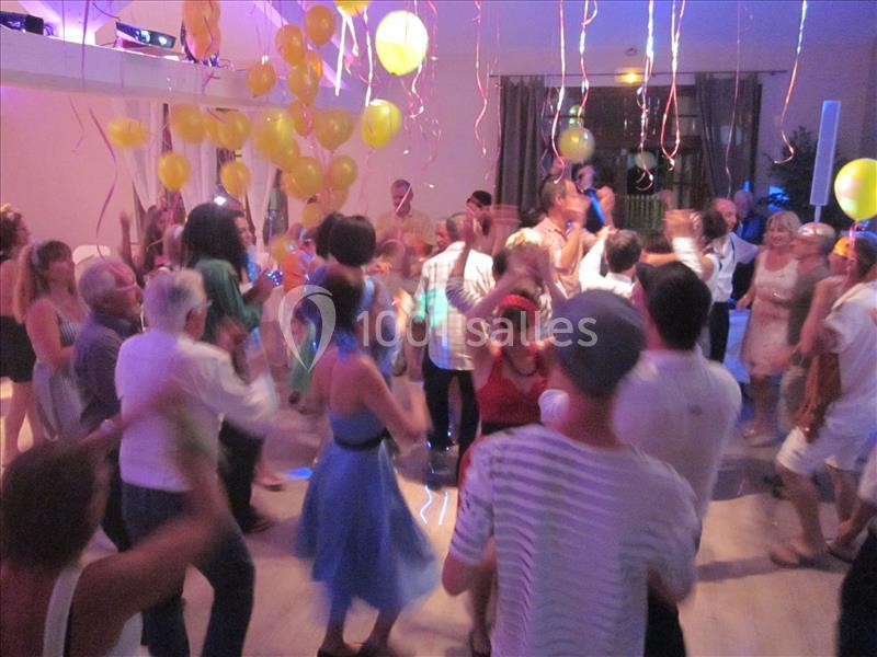 Groupe de personnes dansant dans une salle décorée de ballons et de guirlandes colorées.