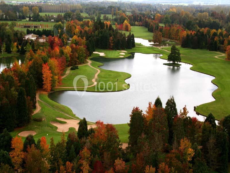 Vue aérienne d'un terrain de golf entouré d'arbres aux couleurs automnales et de plusieurs plans d'eau.