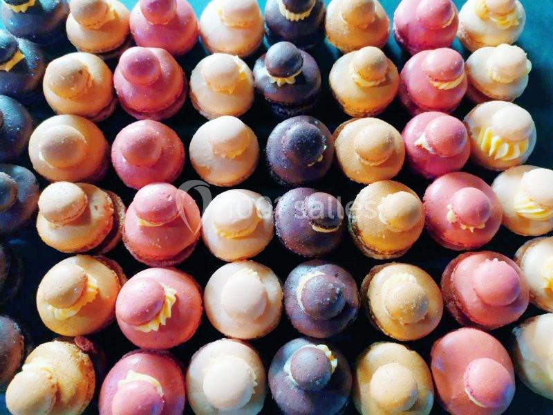 Assortiment de petits macarons colorés disposés en rangées serrées.