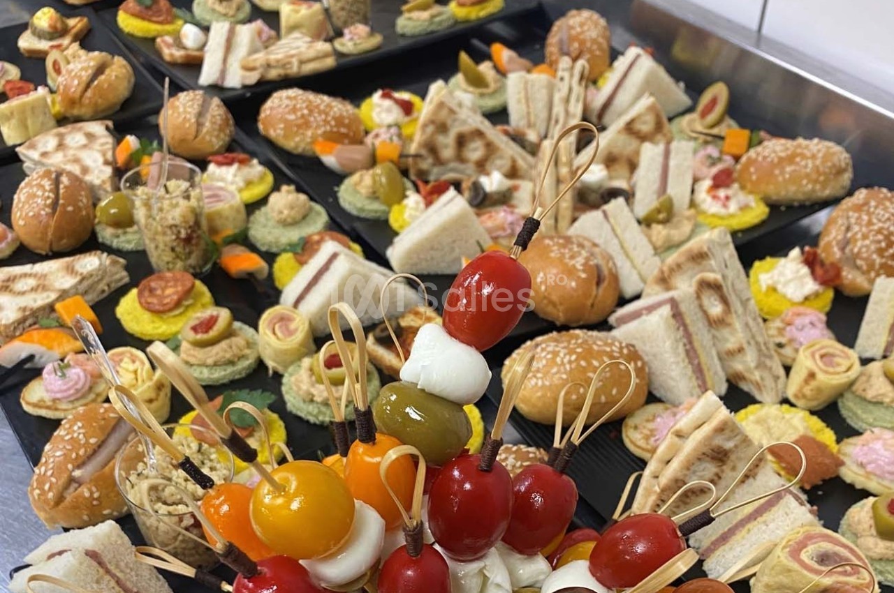 Plateaux garnis de divers amuse-bouches, incluant brochettes de tomates et mozzarella, sandwichs et bouchées variées.