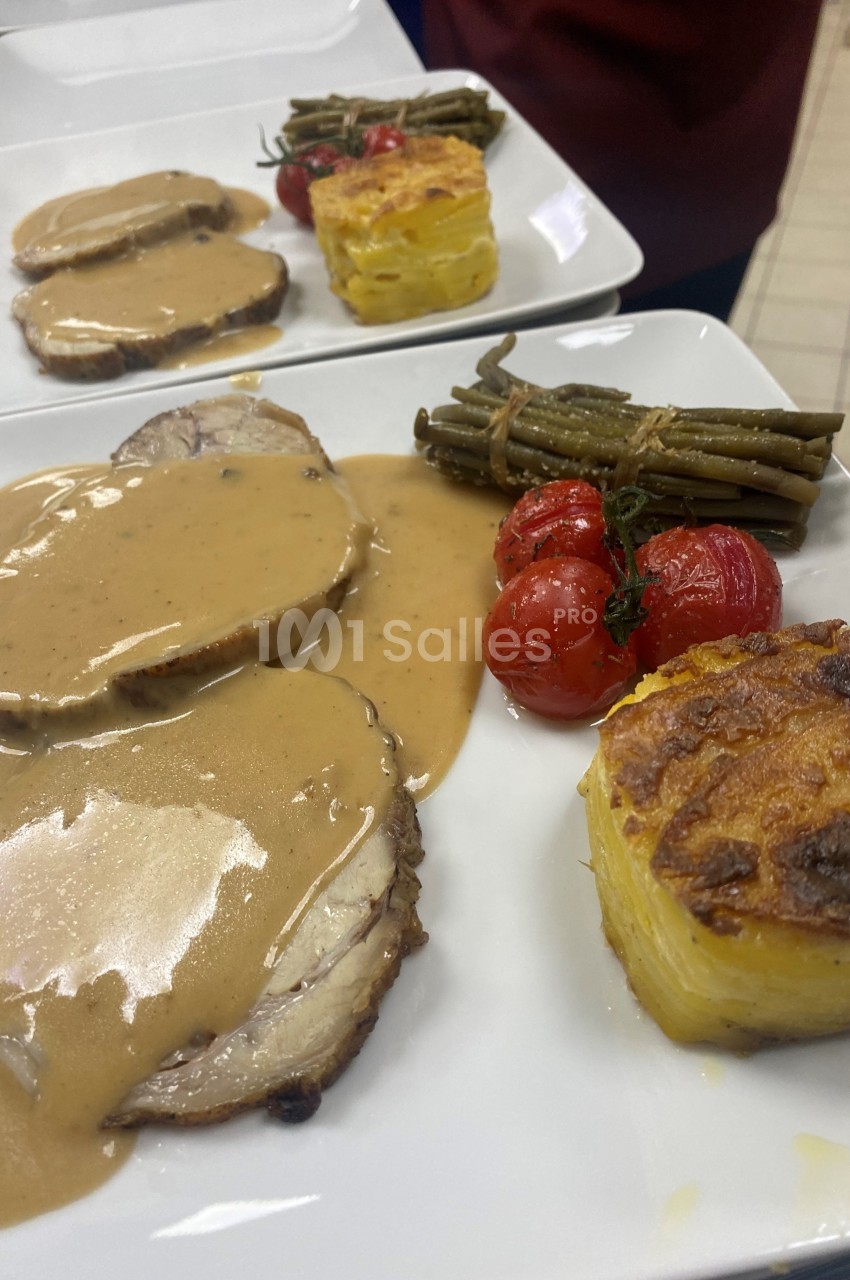 Assiette composée de rôti en sauce, gratin de pommes de terre, haricots verts et tomates cerises rôties.