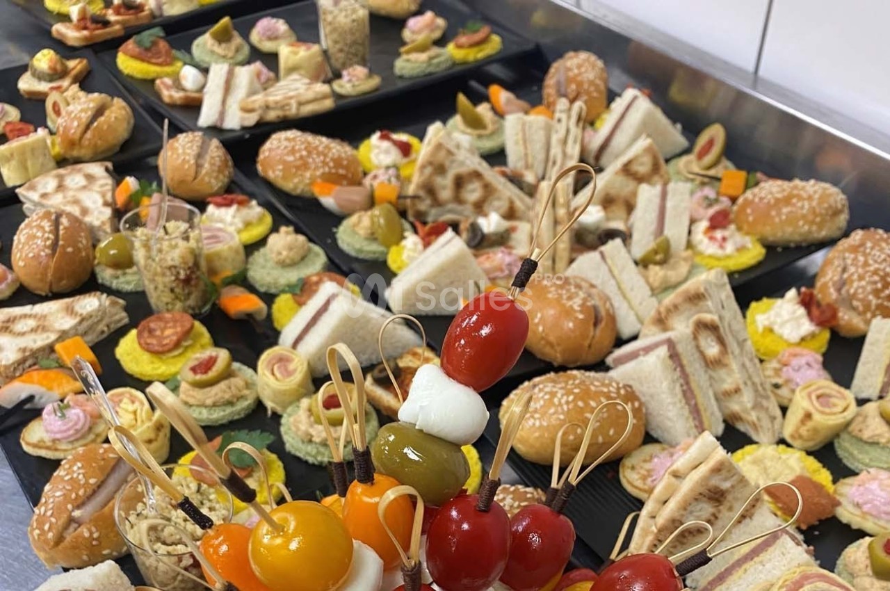 Plateaux garnis de divers amuse-bouches, sandwichs, brochettes et bouchées apéritives disposés sur une table.