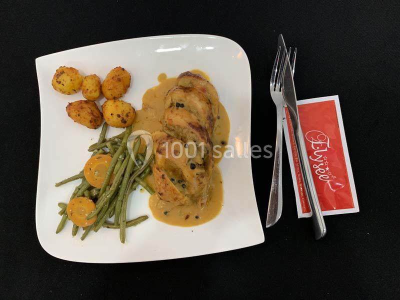 Assiette avec filet de volaille en sauce, haricots verts, carottes, pommes de terre rôties, couverts et serviette rouge.