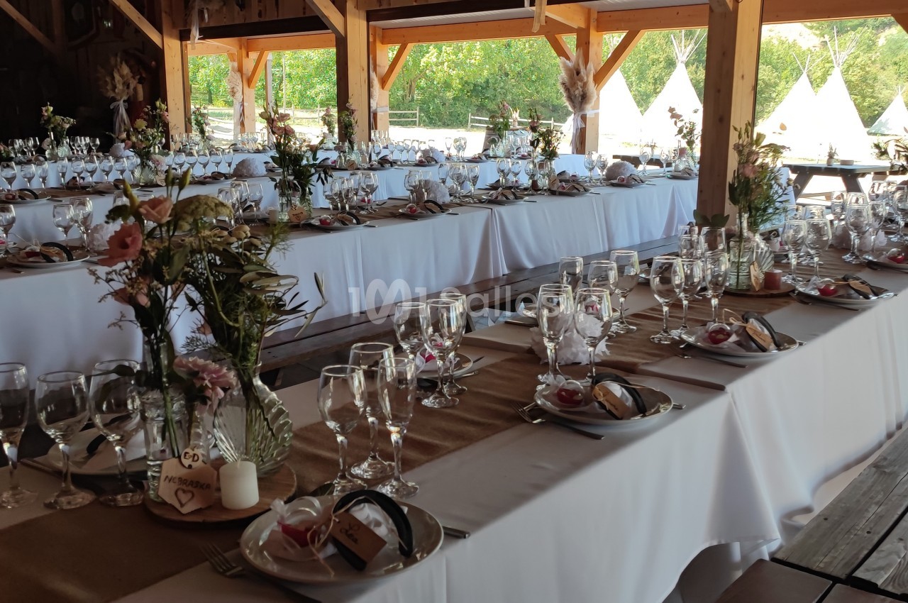 Tables décorées pour un mariage ou un événement, avec nappes blanches, vaisselle élégante et arrangements floraux.
