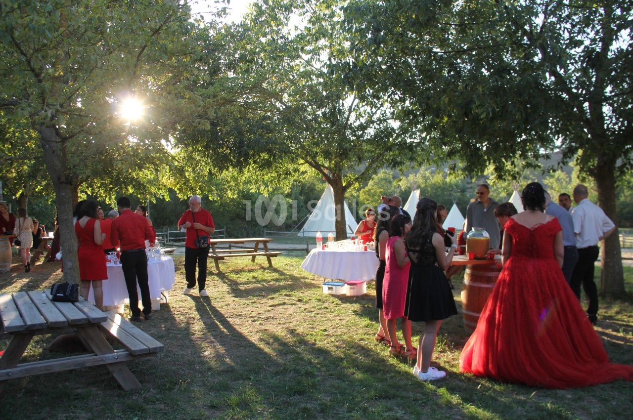 Groupe de personnes rassemblées dans un jardin ensoleillé, près de tables décorées, lors d'un événement festif.