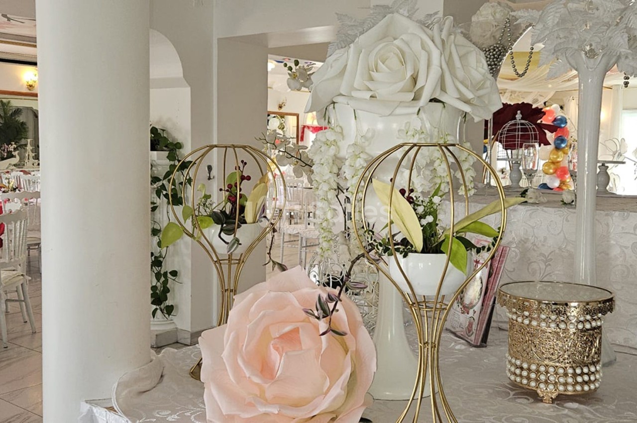 Salle de réception décorée avec des fleurs, des tables dressées et des éléments décoratifs élégants.