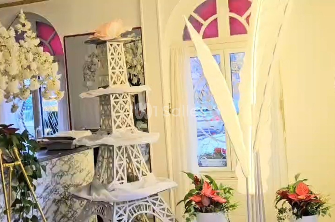 Décoration intérieure avec une tour Eiffel blanche ornée de fleurs, entourée de plantes et d'éléments floraux.