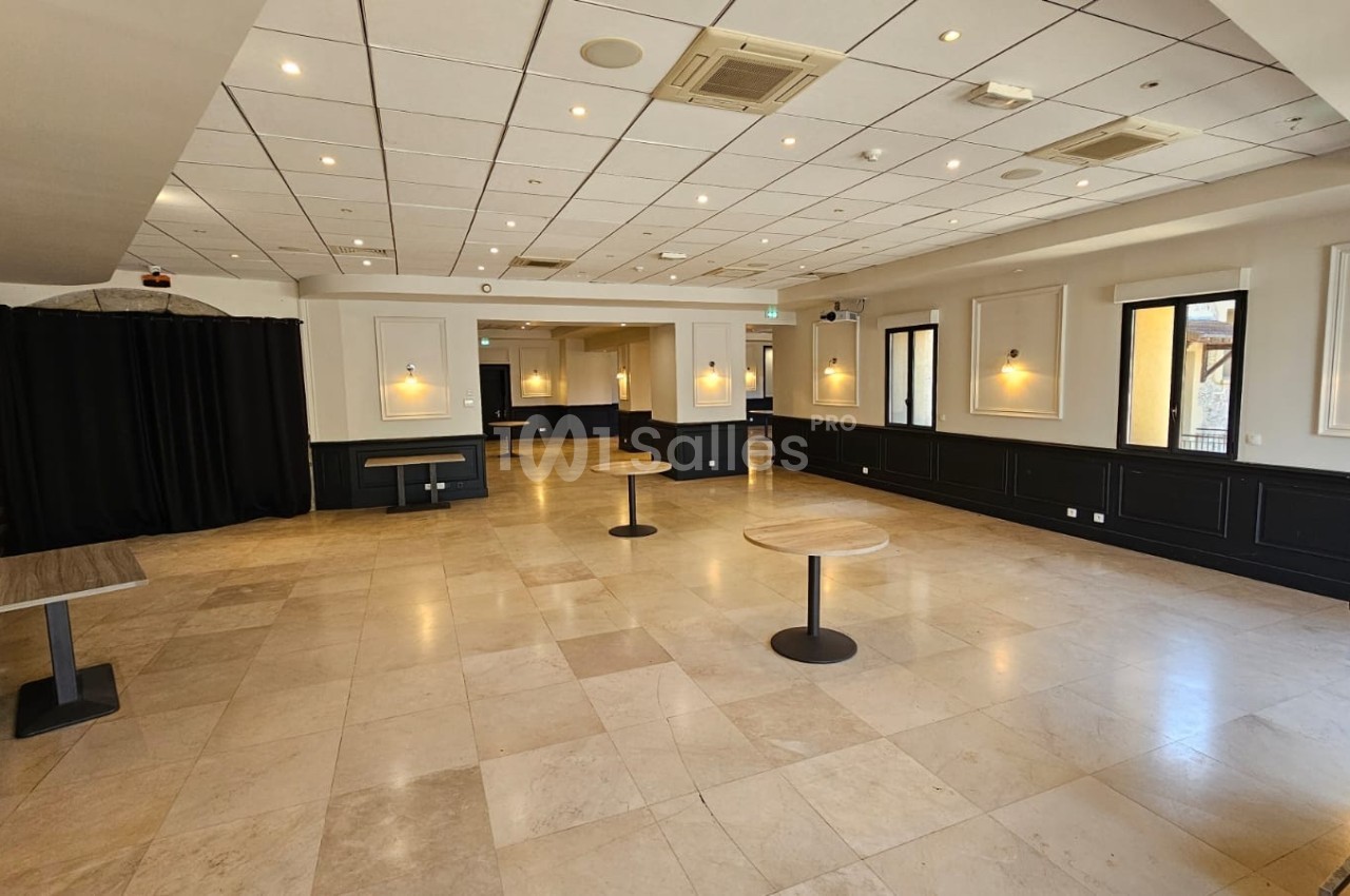 Salle lumineuse avec sol en carrelage clair, murs blancs, éclairage mural et tables rondes espacées.