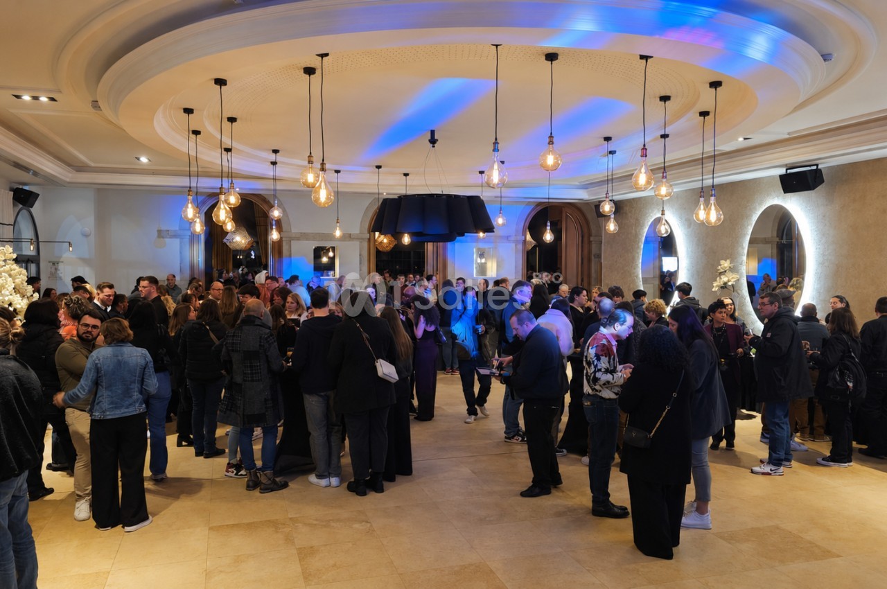 Groupe de personnes rassemblées dans une salle élégante avec éclairage chaleureux et décorations modernes.