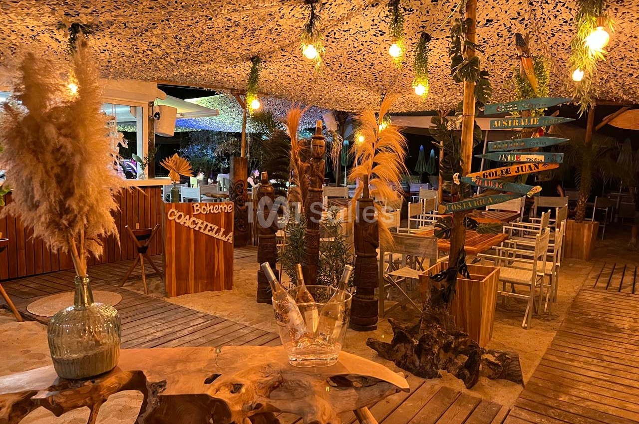 Décoration bohème avec plantes, lumières suspendues et mobilier en bois dans un espace extérieur chaleureux.