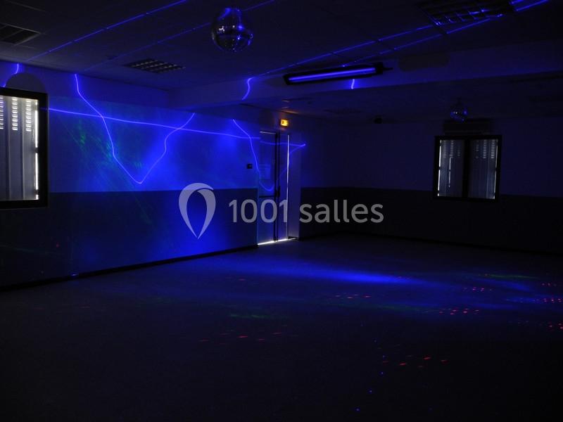 Salle sombre avec des lumières bleues et violettes projetées sur les murs et le sol, créant une ambiance lumineuse.
