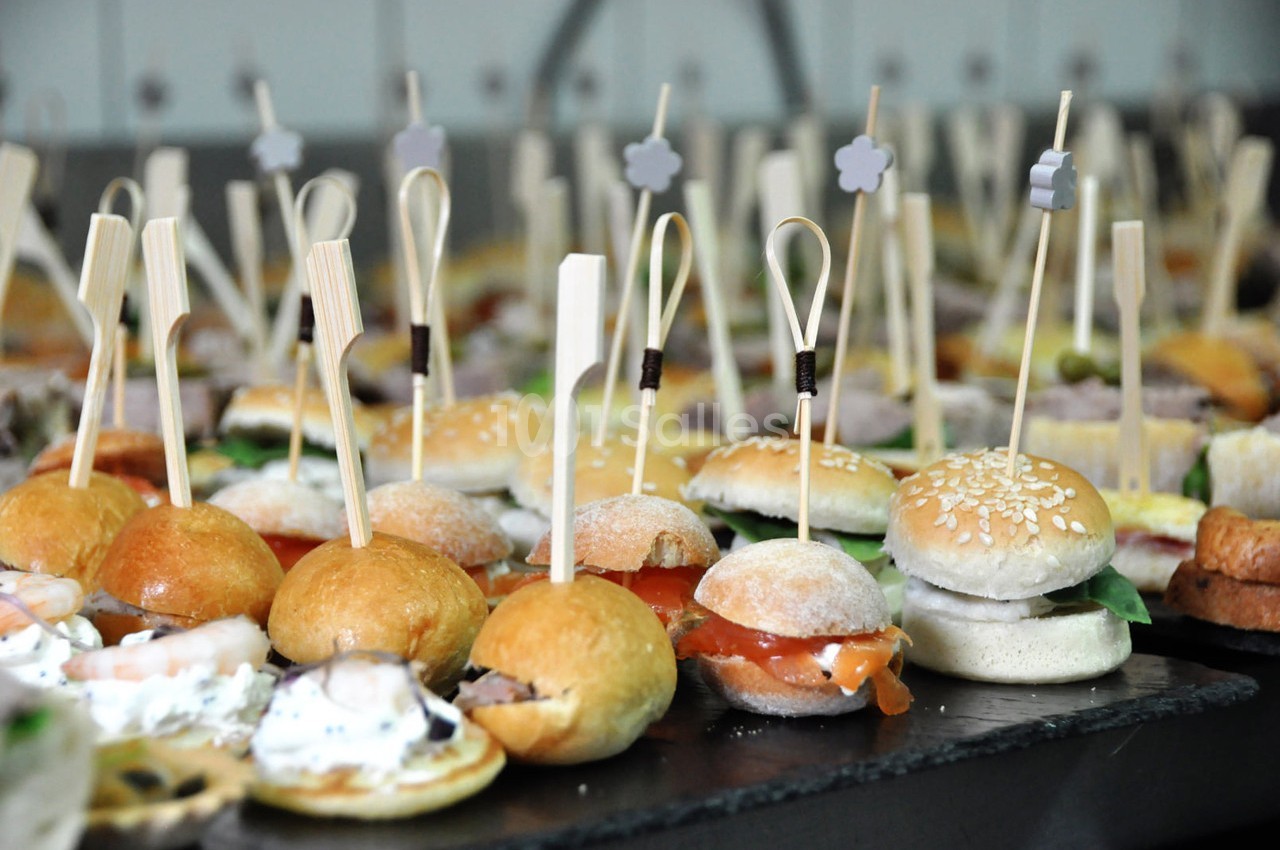 Plateau de mini-sandwichs variés présentés sur des piques en bois, disposés sur une table noire.