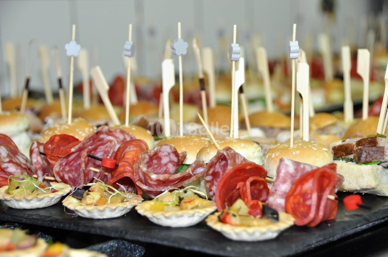 Plateau de bouchées apéritives variées comprenant mini-burgers, charcuterie et tartelettes garnies.