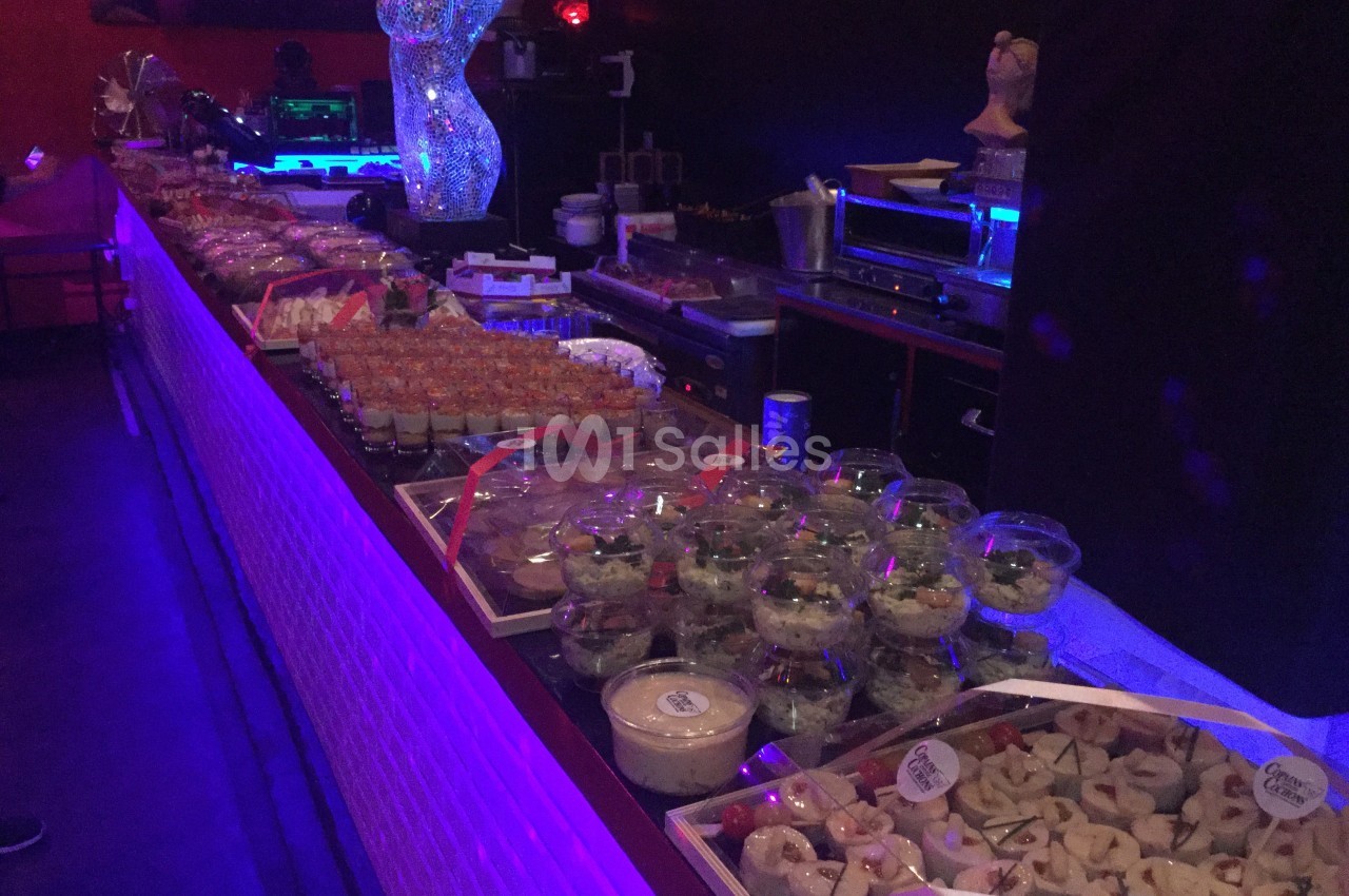 Buffet varié avec verrines, salades et amuse-bouches disposés sur une longue table dans un éclairage tamisé.