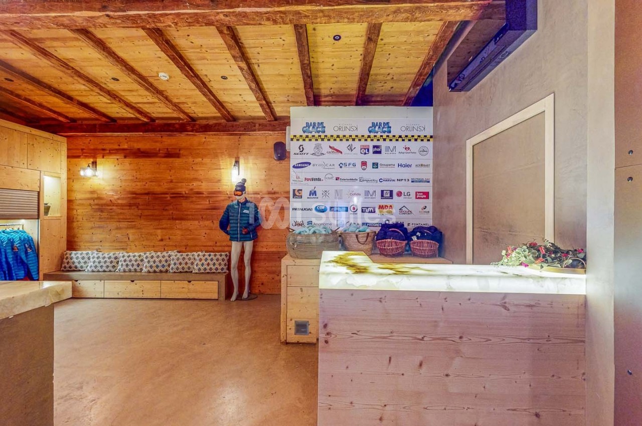 Intérieur d'un espace en bois avec un comptoir, un mannequin habillé, des étagères et un mur affichant des logos.