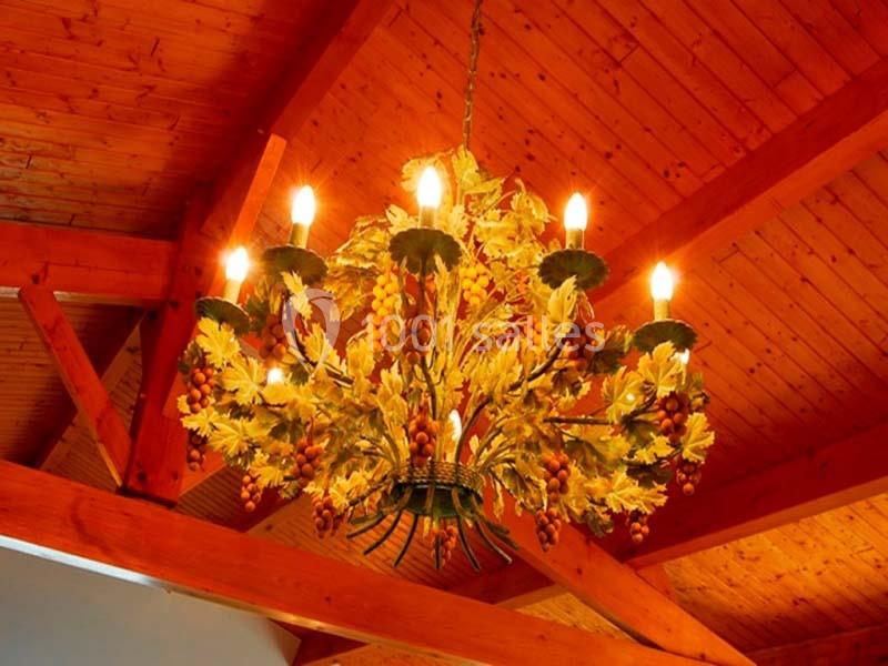 Lustre décoratif en métal orné de feuilles et de baies, suspendu sous un plafond en bois.