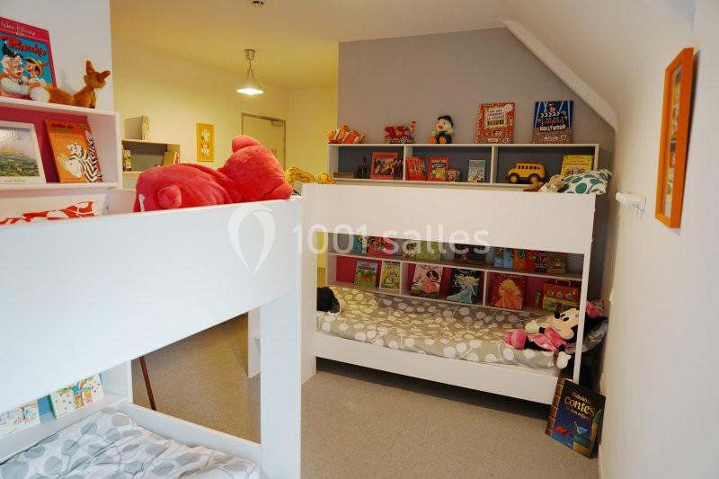 Chambre d'enfants avec lits superposés, étagères remplies de livres et jouets colorés.