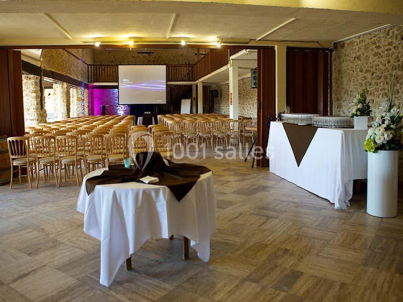 Salle de réception avec chaises alignées, écran de projection, table nappée et buffet préparé.