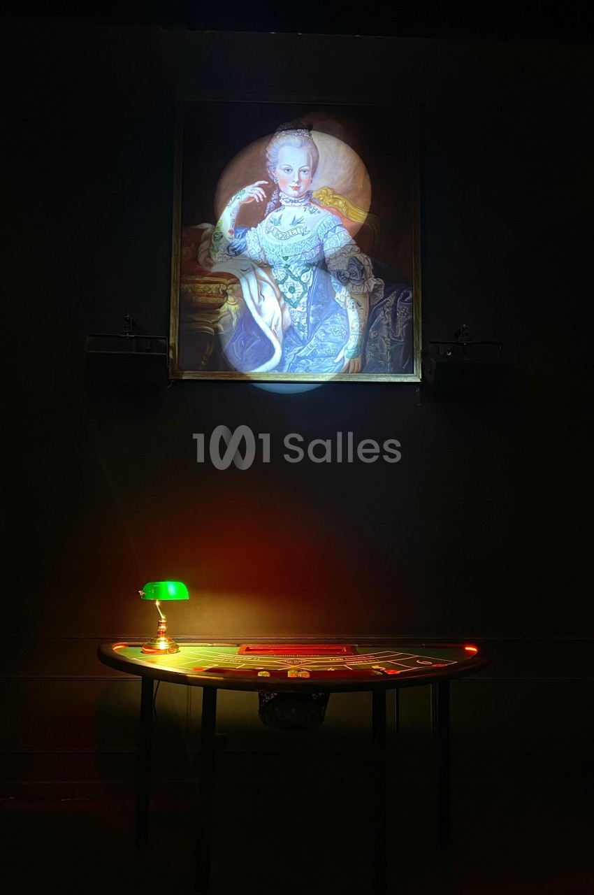 Portrait éclairé d'une femme en tenue d'époque, suspendu au-dessus d'une table ronde avec une lampe verte allumée.
