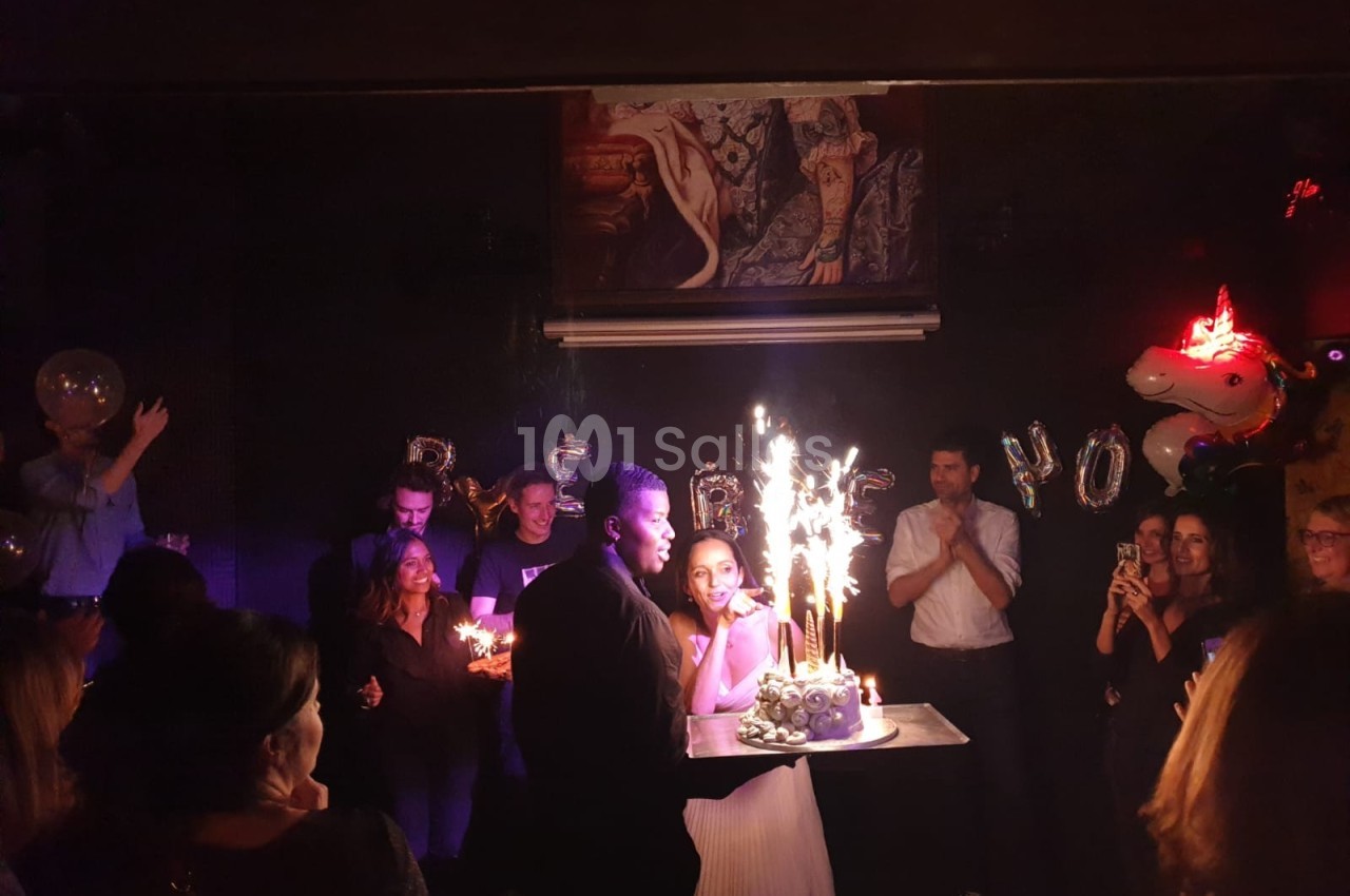 Un couple souffle des bougies sur un gâteau avec des cierges étincelants lors d'une fête en soirée.
