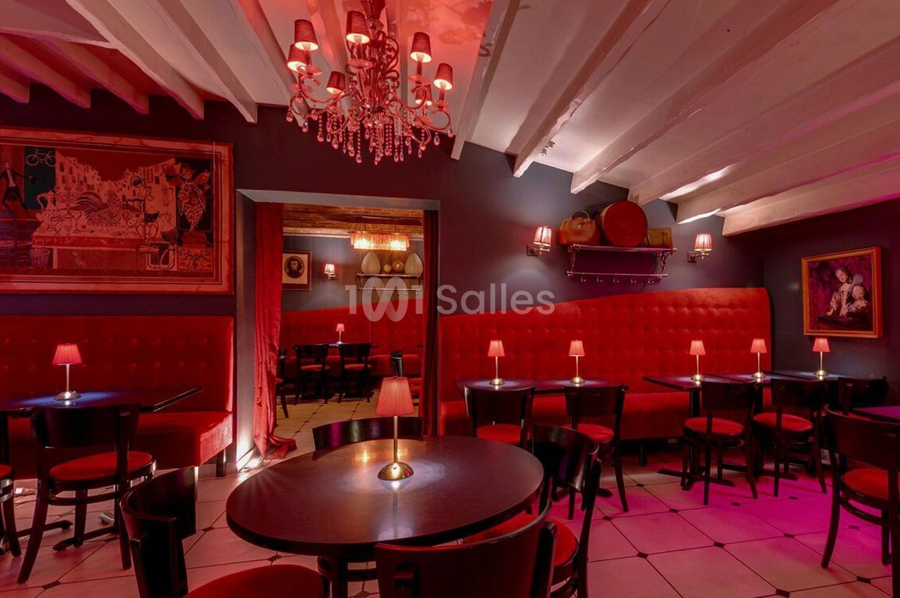 Salle de restaurant avec banquettes rouges, tables rondes, éclairage tamisé et décorations murales.