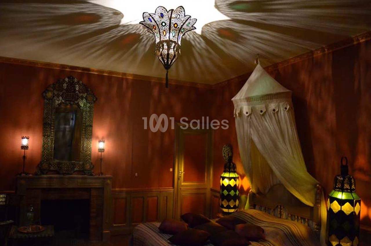 Chambre décorée dans un style oriental avec un lit à baldaquin, des lampes colorées et un éclairage tamisé.