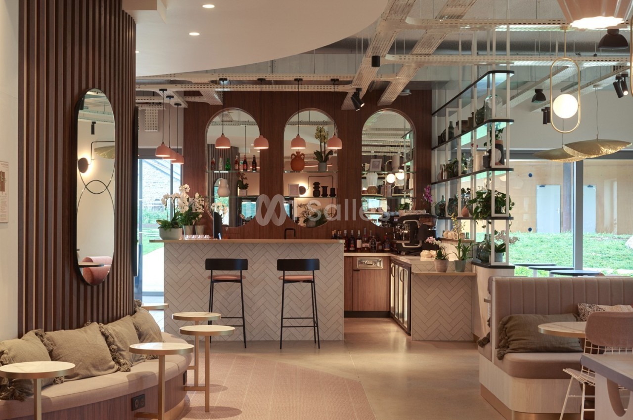 Espace intérieur moderne avec bar central, mobilier en bois, miroirs arrondis et lumière naturelle entrant par une baie…