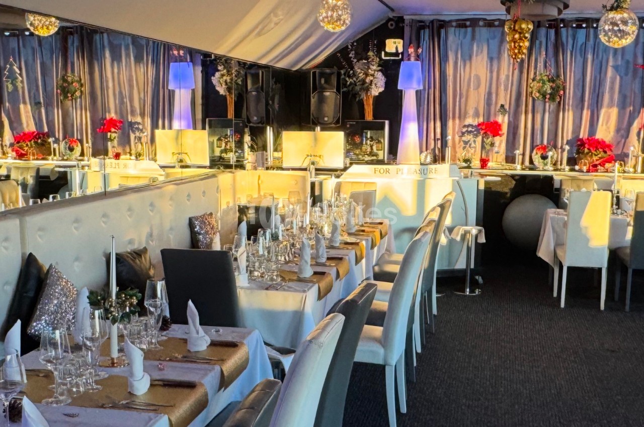 Salle de réception élégante avec tables dressées, décorations festives, et éclairage chaleureux.