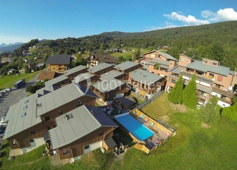 Vue aérienne d'un complexe résidentiel en montagne avec une piscine extérieure et des espaces verts.