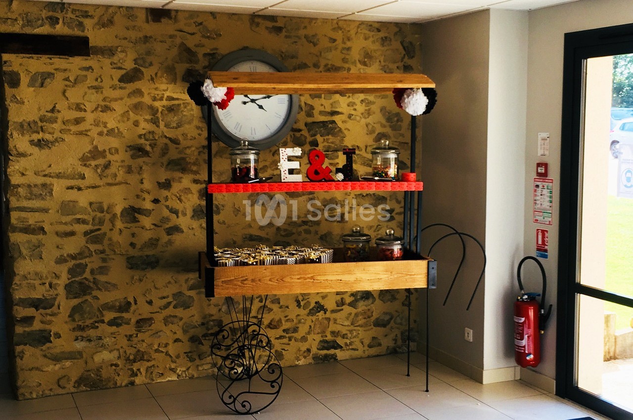 Table décorative avec des bonbonnières, des lettres ’E & T’ et des friandises, placée devant un mur en pierre.