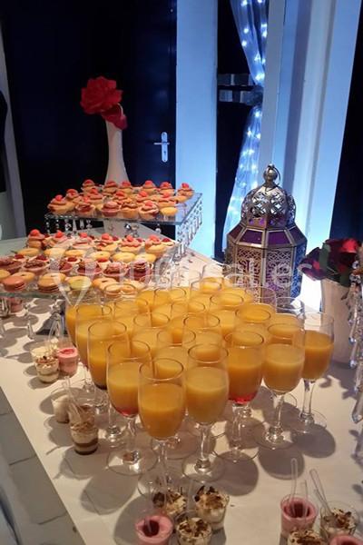 Table garnie de verrines, jus d'orange, pâtisseries et une lanterne décorative dans un cadre lumineux.