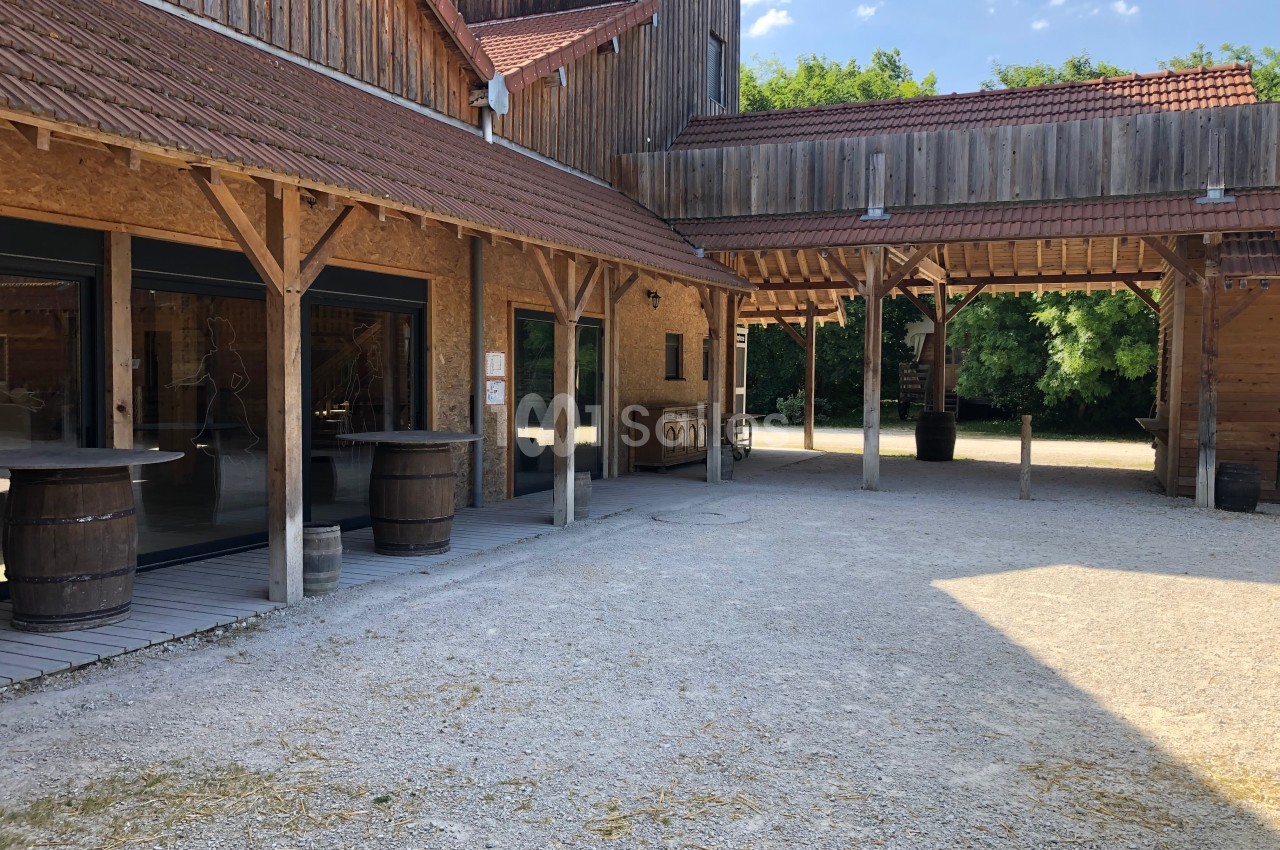 Cour intérieure d'un bâtiment en bois avec des toits en tuiles, des tonneaux et un sol en gravier.