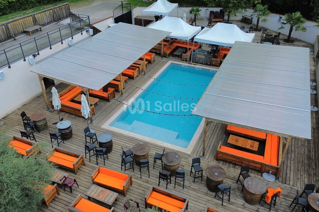 Vue aérienne d'une terrasse avec piscine centrale, entourée de tables, chaises et banquettes orange sous des pergolas.