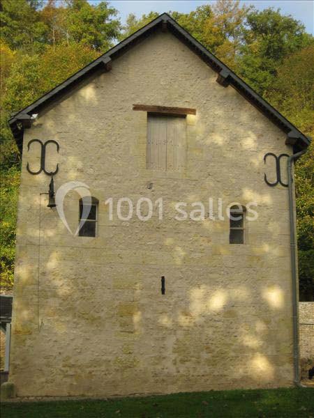 Façade en pierre d'un bâtiment ancien avec deux petites fenêtres, une porte en hauteur et un décor sobre.