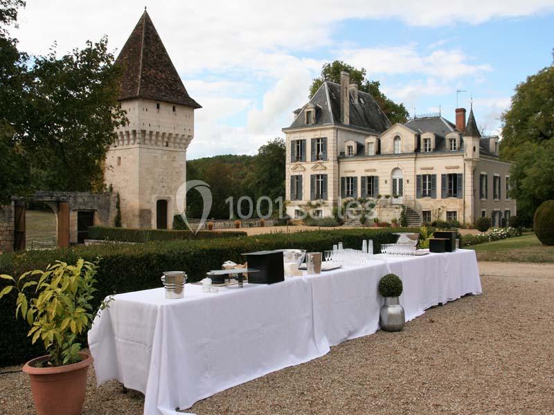 Table dressée pour un événement en extérieur devant un château et une tour dans un cadre verdoyant.