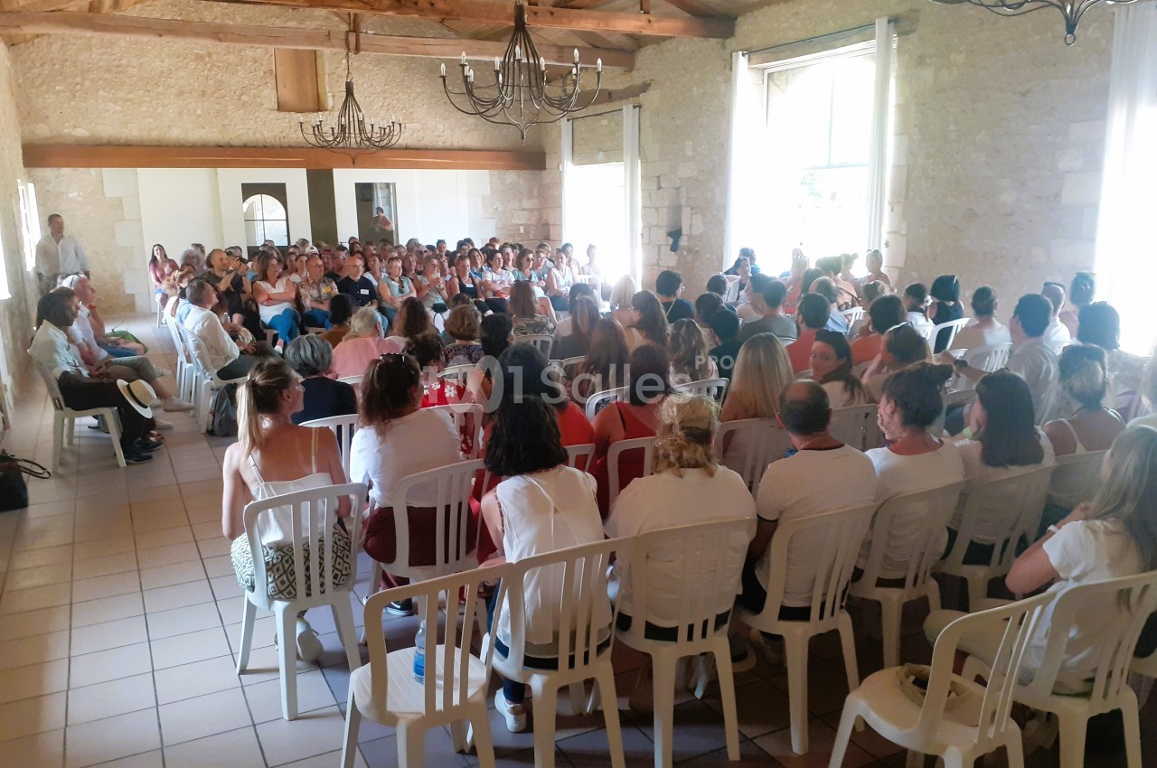 Un groupe de personnes assises dans une salle lumineuse en pierre, participant à une réunion ou une conférence.