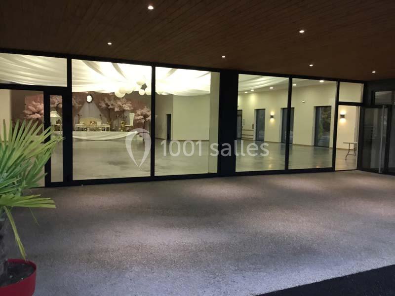 Vue extérieure d'une salle de réception avec de grandes baies vitrées laissant entrevoir une décoration lumineuse.