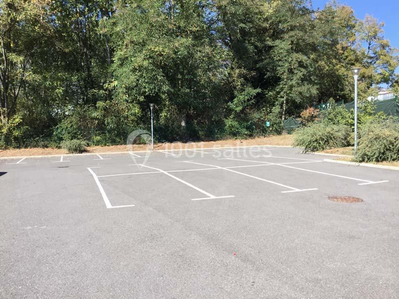 Parking vide entouré de végétation et d'arbres sous un ciel dégagé.