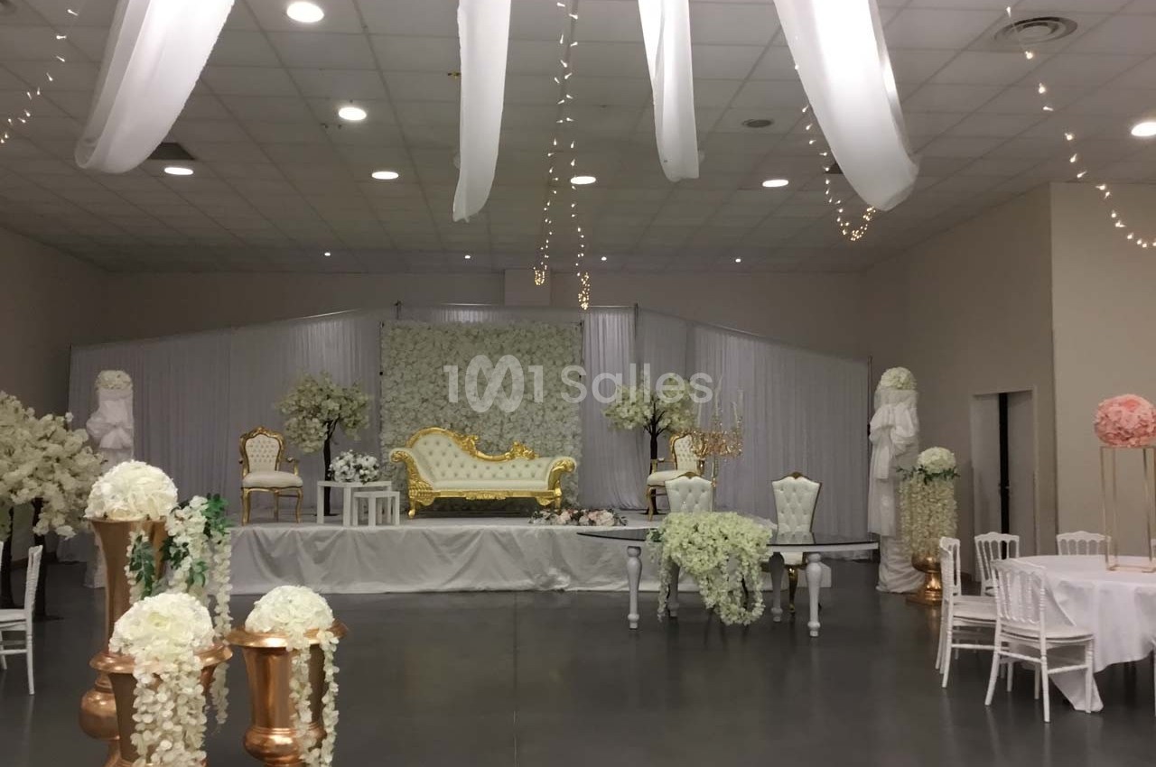 Salle de réception décorée avec des fleurs blanches, des statues, un canapé doré et des chaises élégantes.