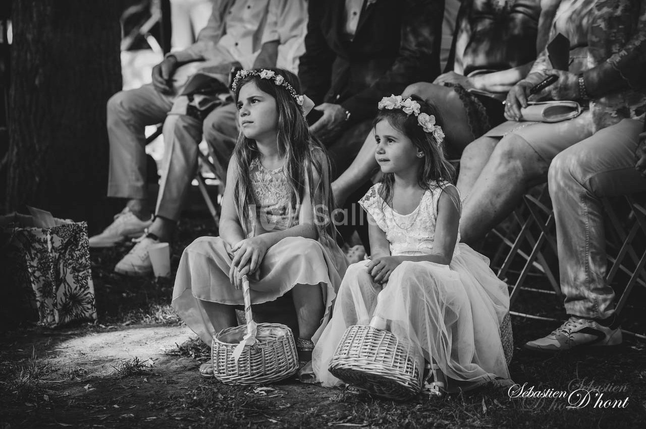 Deux jeunes filles assises sur l'herbe, portant des robes et des couronnes de fleurs, tenant des paniers en osier.
